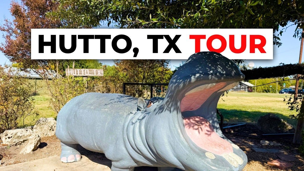 Giant hippo statue in Hutto, Texas, with open mouth, trees, and sign in the background.
