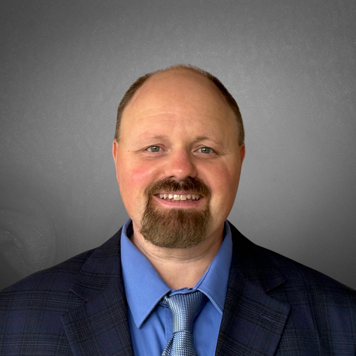 A man with a beard is wearing a suit and tie and smiling.