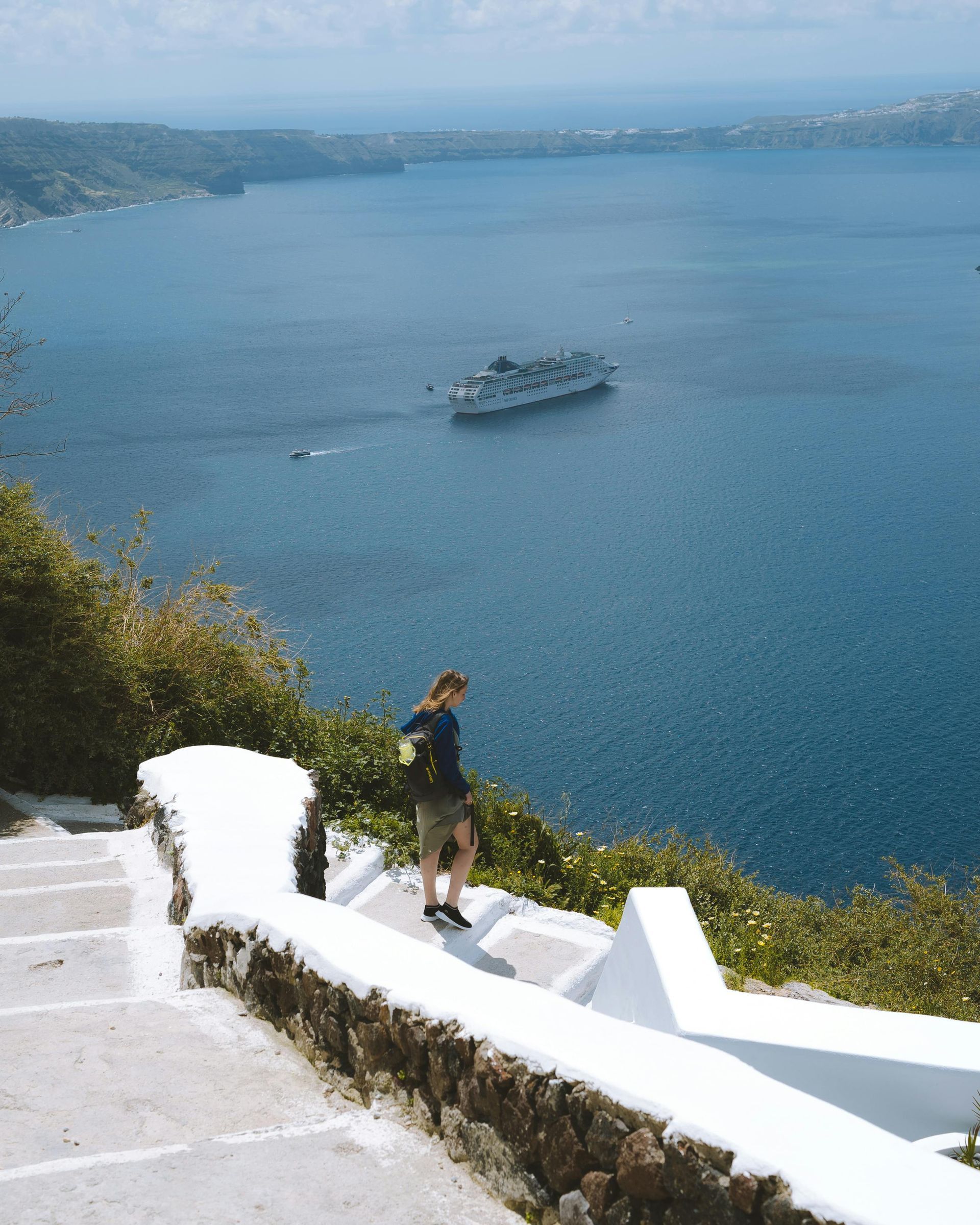 A person standing on a cliff overlooking a body of water