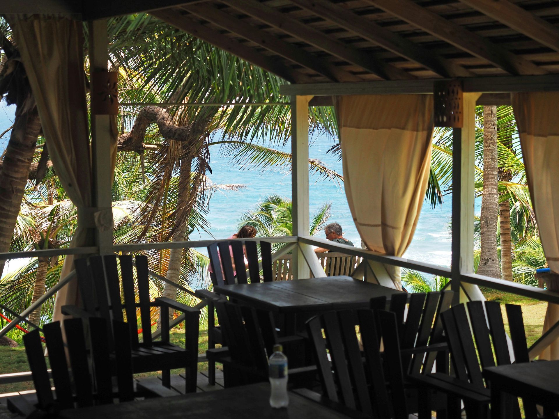 A man sits on a balcony overlooking the ocean
