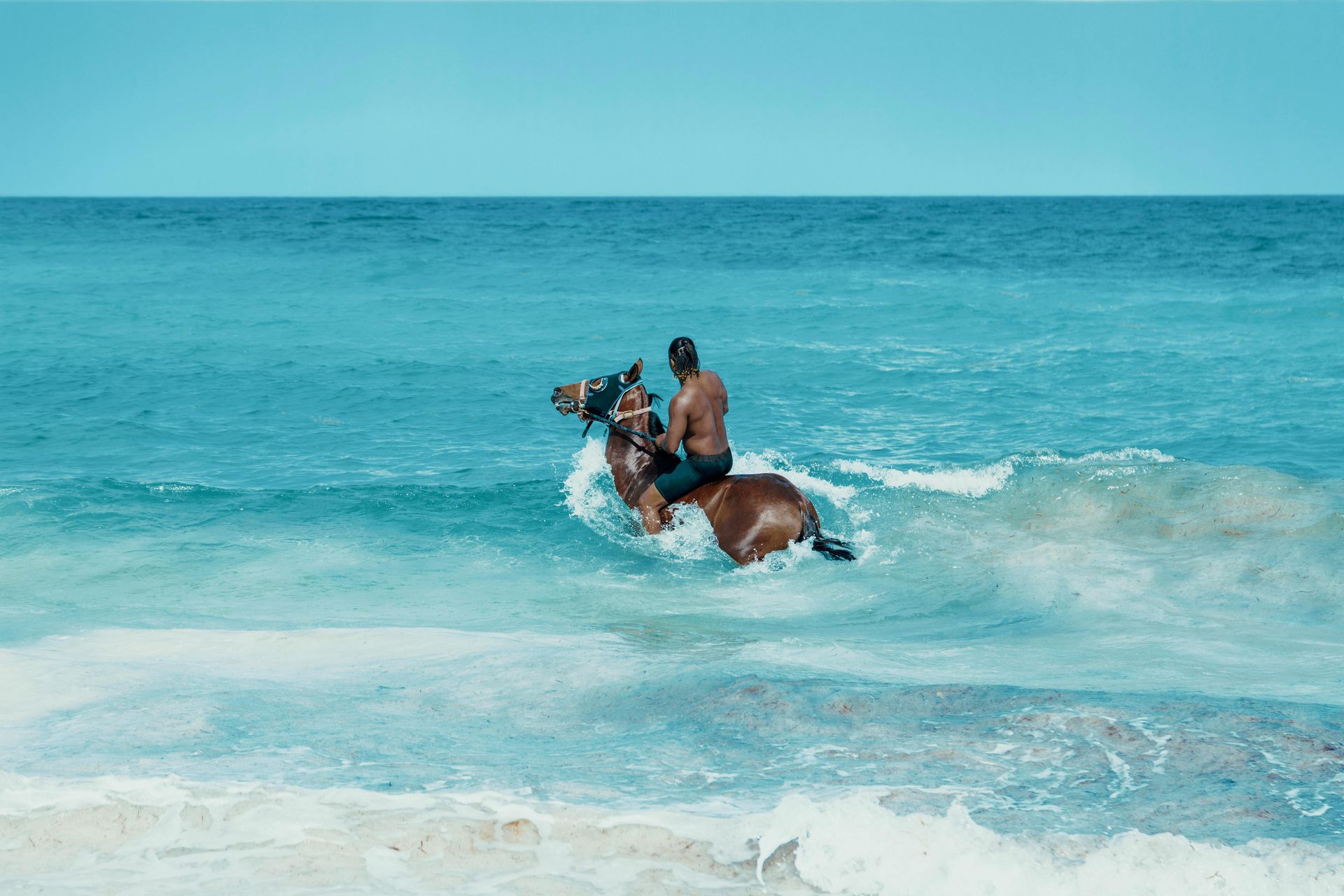 A man is riding a horse in the ocean.