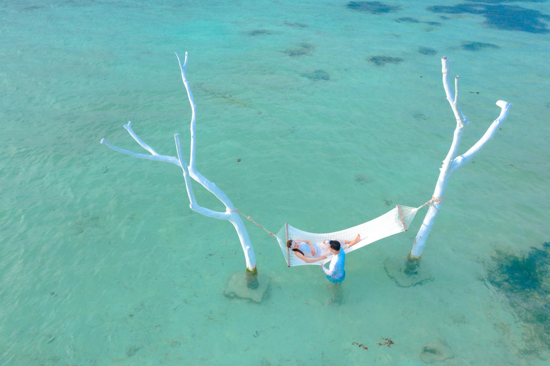 A person is laying in a hammock in the ocean.