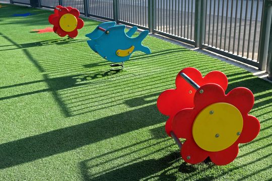 A row of colorful rocking horses in the shape of flowers and fish