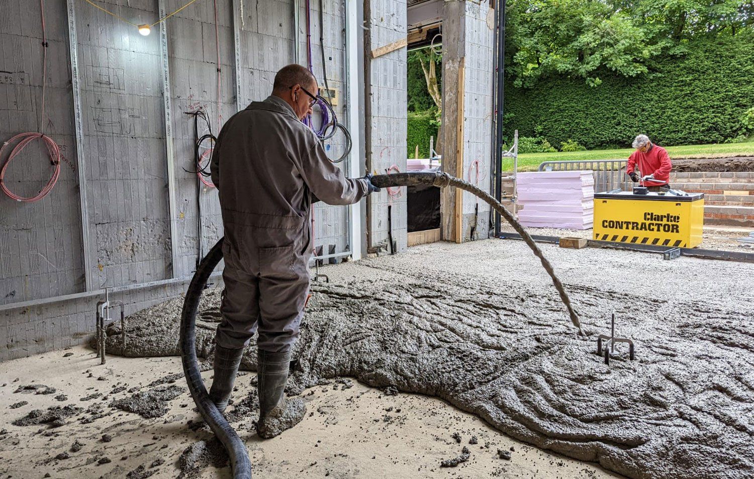 a member of clockwork laying the screed on to floor using hose