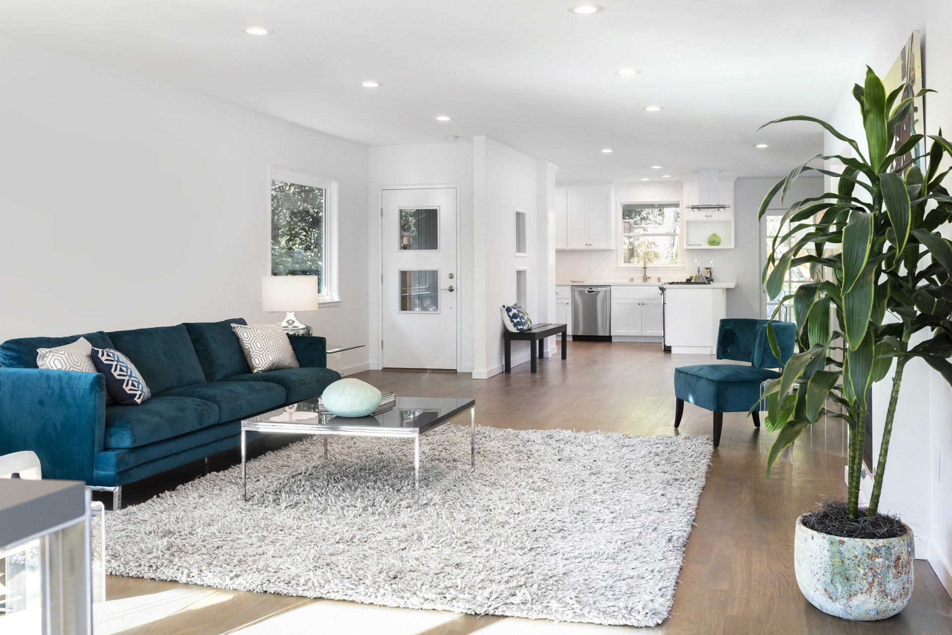 A living room with a blue couch and a white rug.