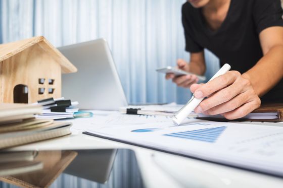 A man is sitting at a desk holding a pen and a cell phone.