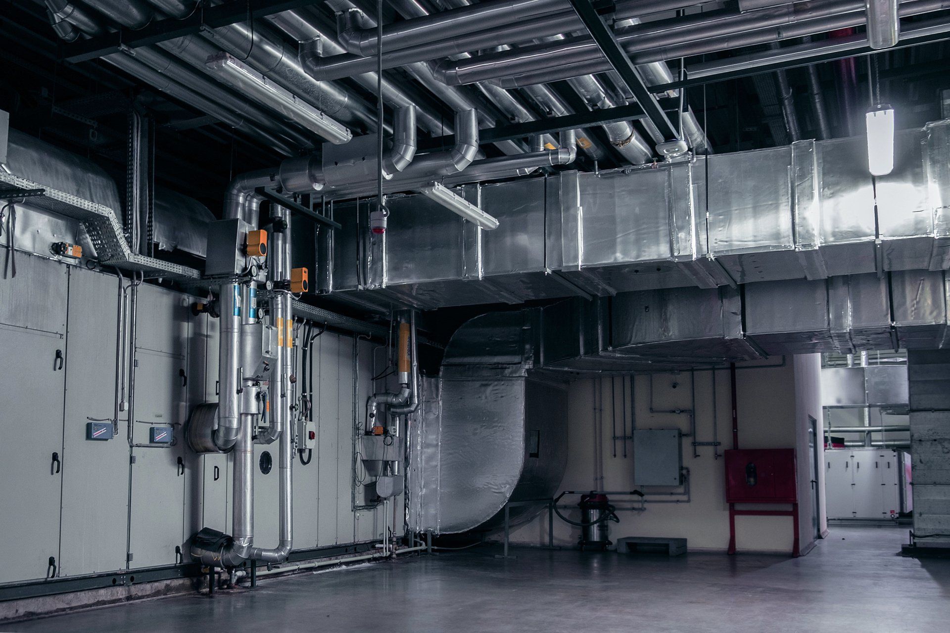 There are a lot of pipes hanging from the ceiling in this room.