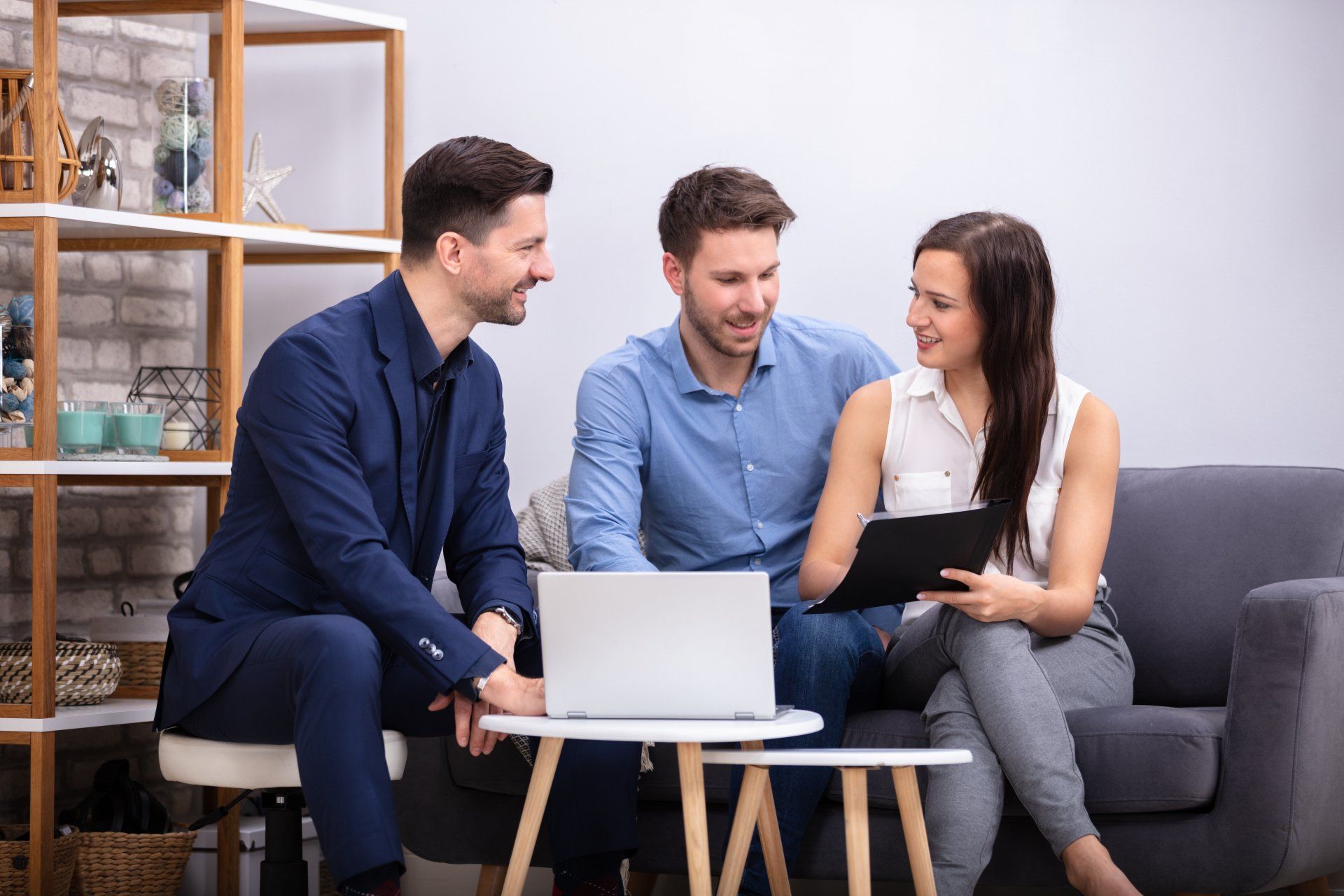 A man and a woman are sitting on a couch looking at a laptop.