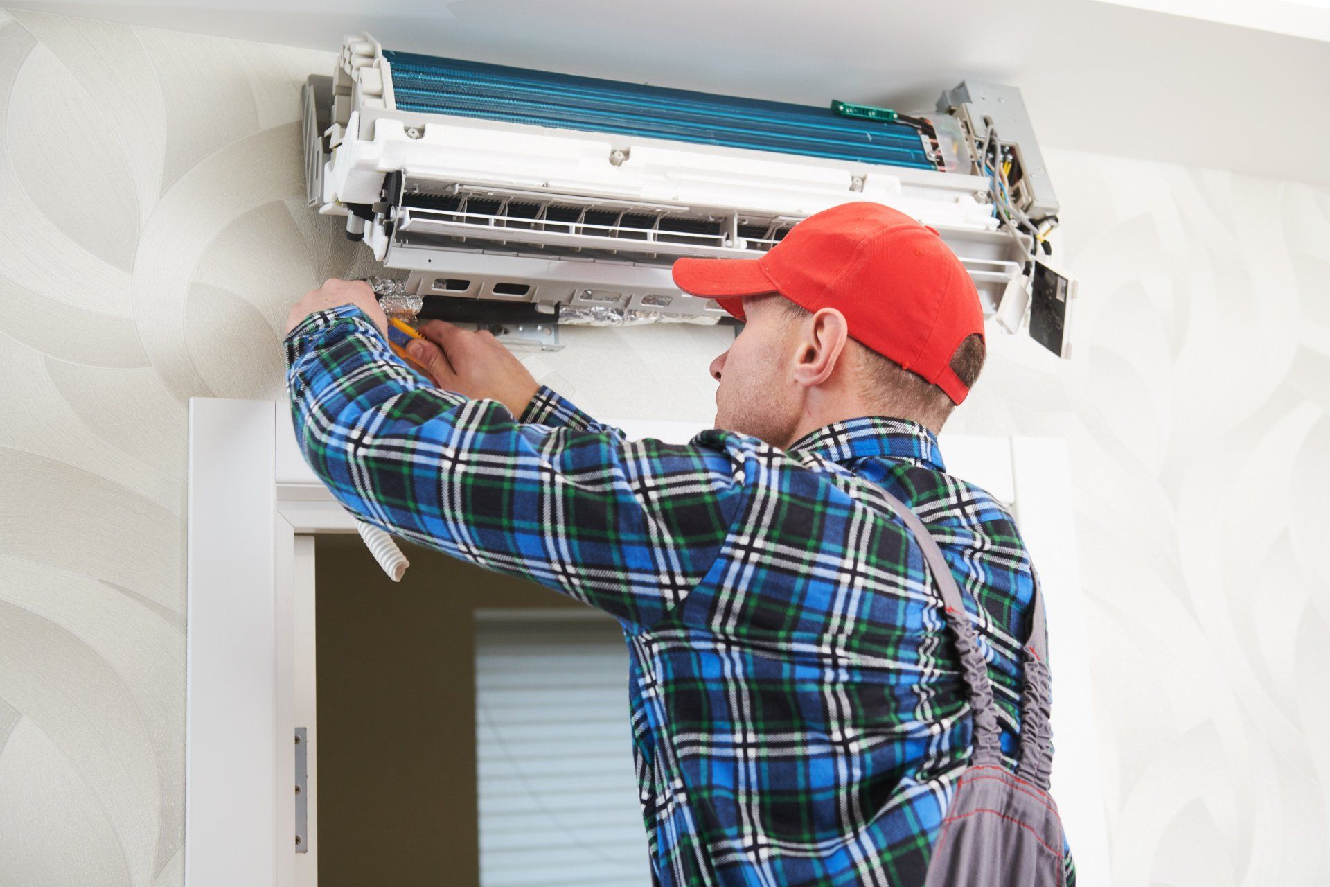 A man is fixing an air conditioner on the wall.