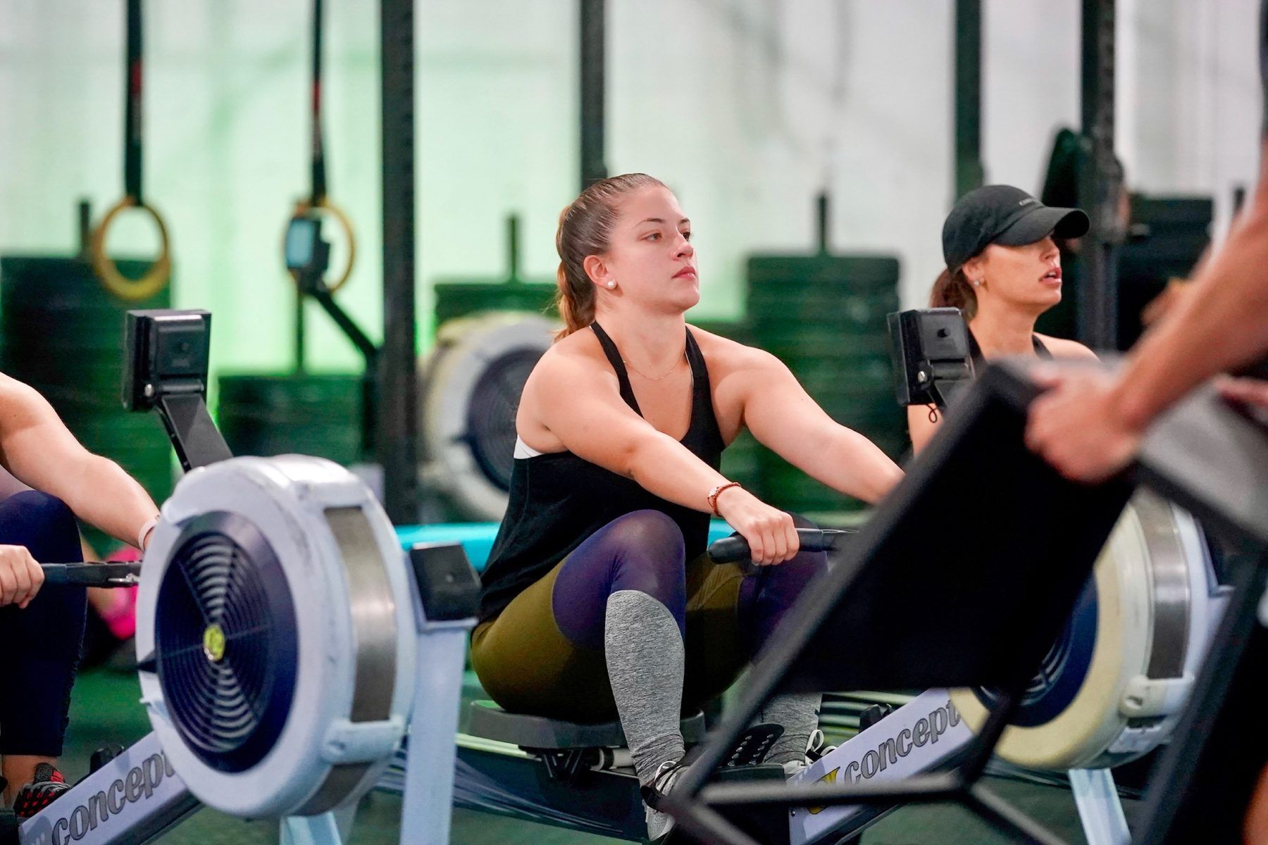 A group of people are riding rowing machines in a gym.