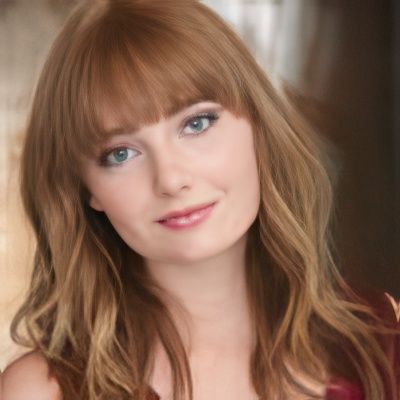 A close up of a woman 's face with long hair and bangs
