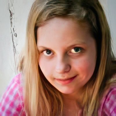 A close up of a young girl 's face wearing a pink shirt.