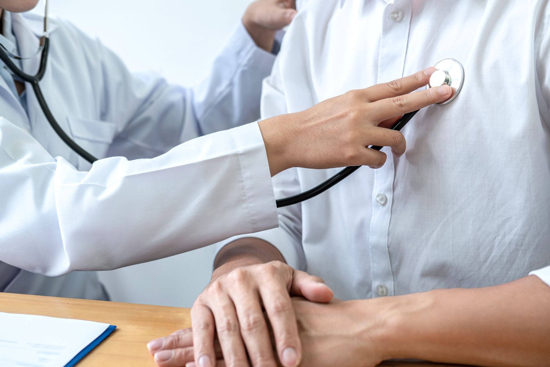 Doctor using a stethoscope to listen to a patient's chest in an office setting.