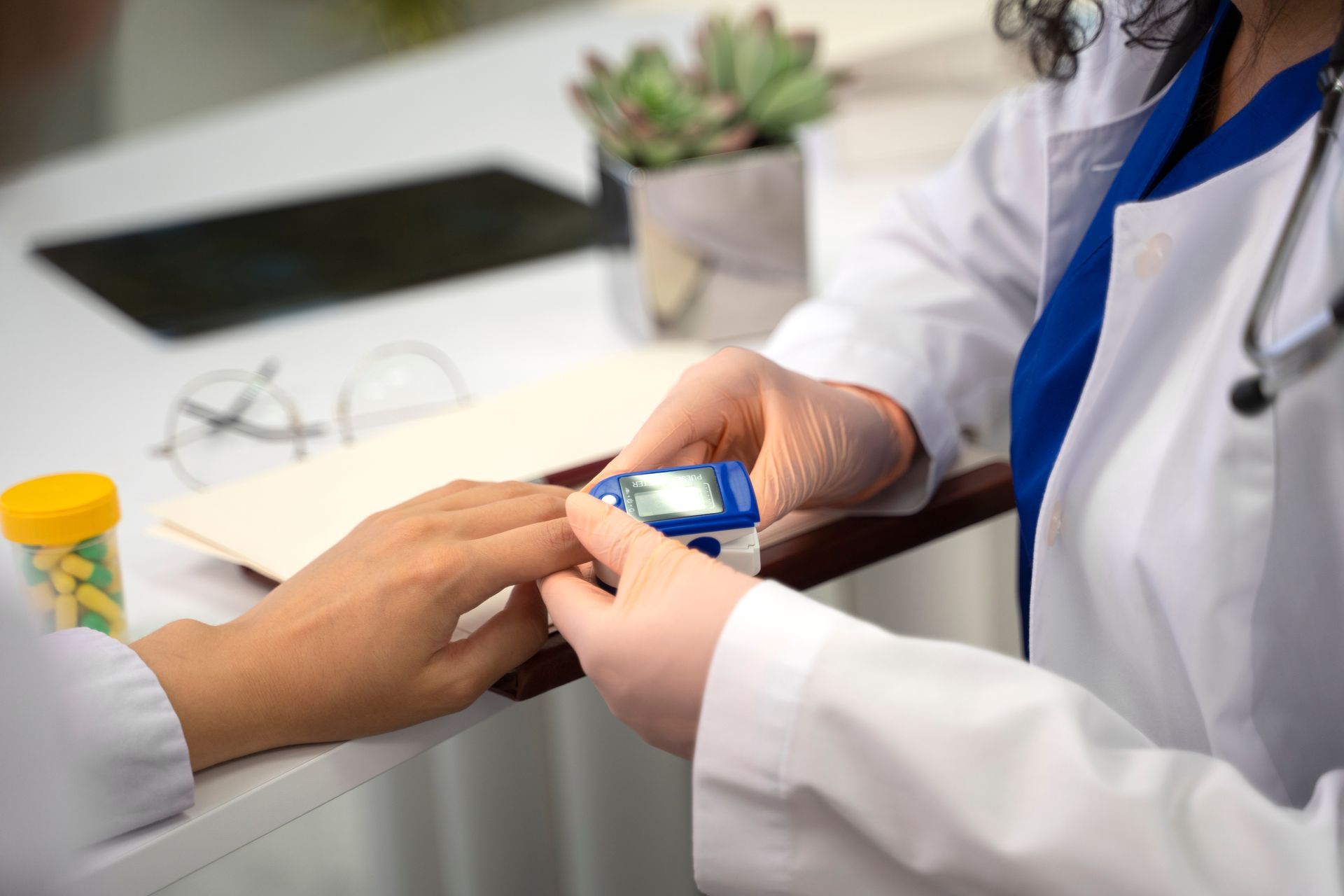 Doctor using a pulse oximeter on a patient's finger in a medical setting.