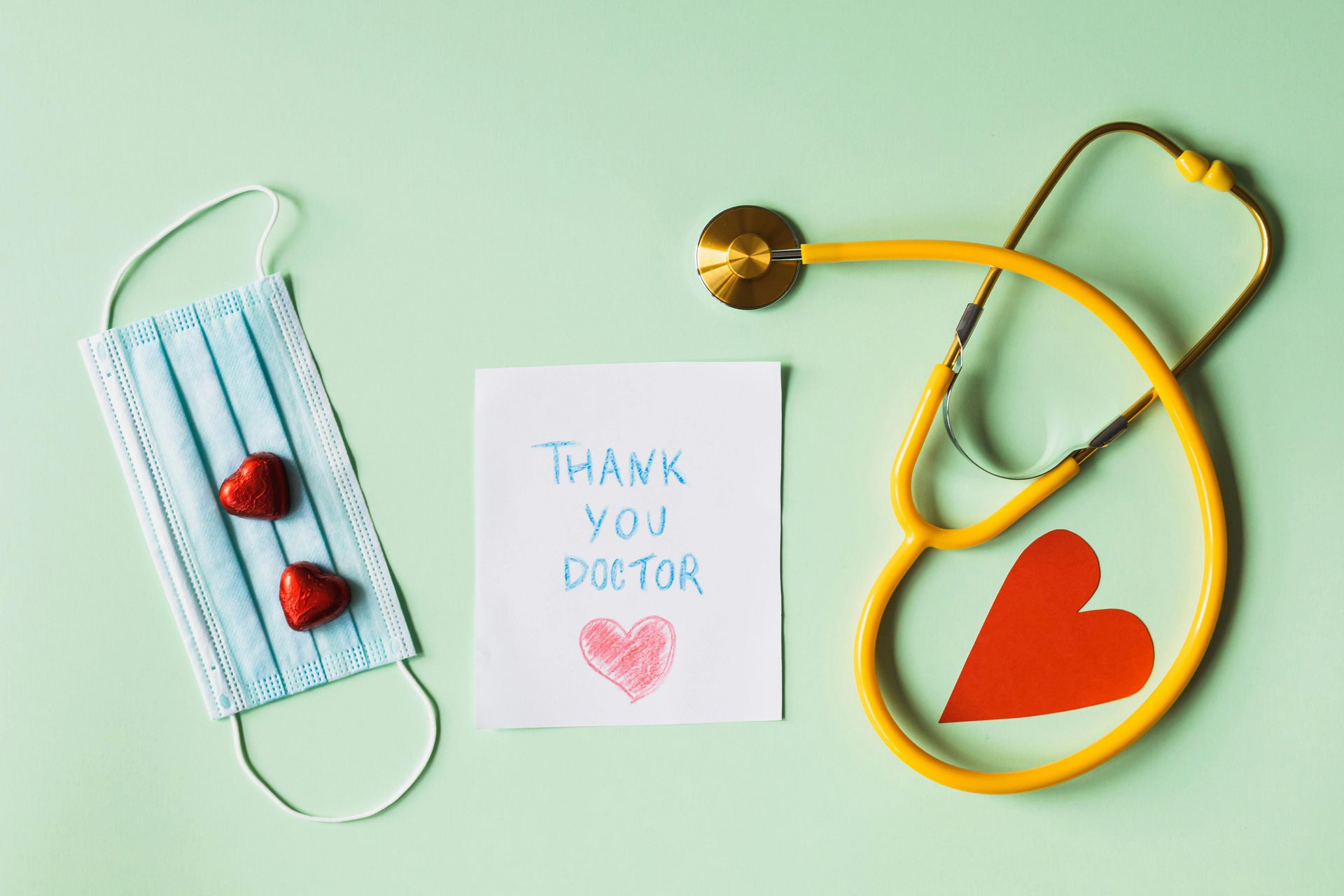 Medical-themed thank-you. Blue mask, red hearts, stethoscope, and a card that says
