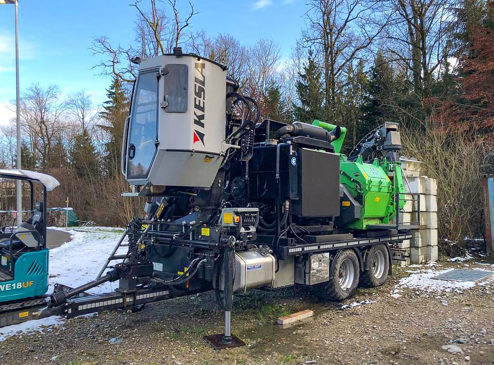 Una grande macchina verde e bianca è parcheggiata in un campo innevato.