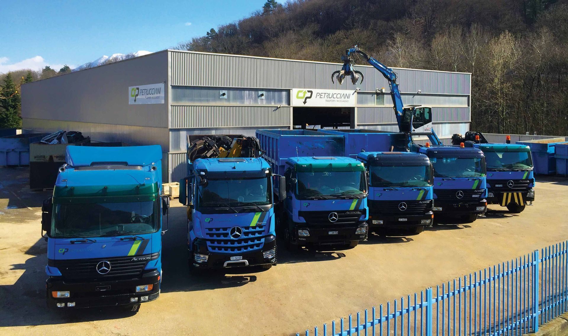Una fila di camion blu è parcheggiata davanti a un edificio
