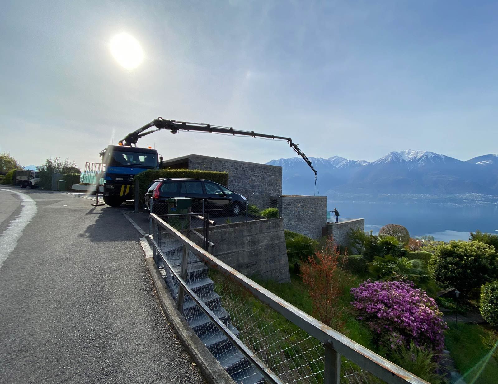 Una camion con una gru è ferma sul lato di una strada accanto a una casa con vista lago.