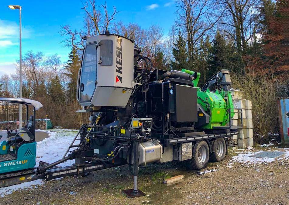 Una grande macchina verde e bianca è parcheggiata in un parcheggio di ghiaia.