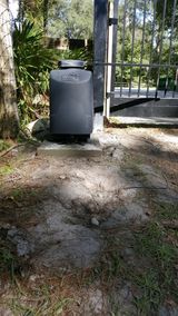 A black box is sitting in the dirt next to a gate.