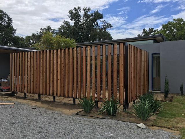 A wooden fence is in front of a house.