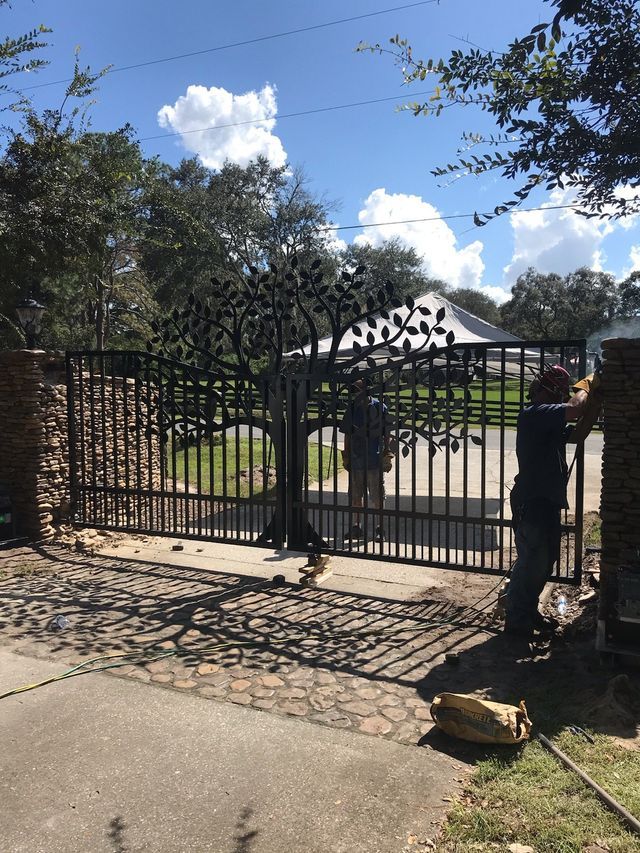 A man is working on a gate with a tree design on it