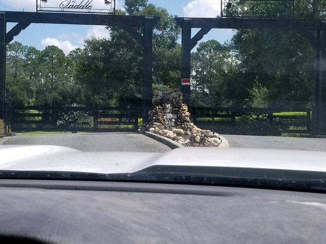 A car is driving past a gate with a waterfall in front of it.