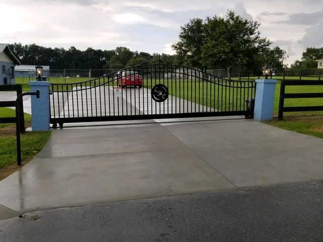 A red car is parked in a driveway behind a sliding gate