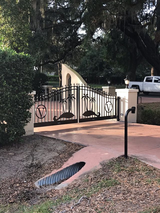A white truck is parked in front of a wrought iron gate