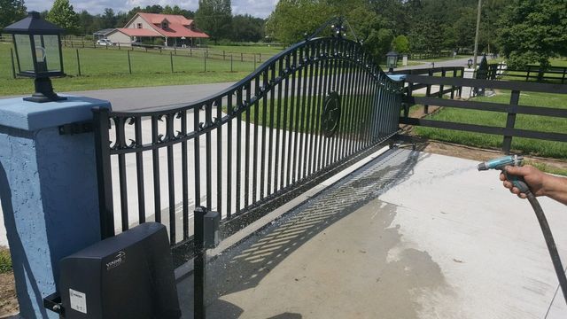 A person is cleaning a gate with a hose.