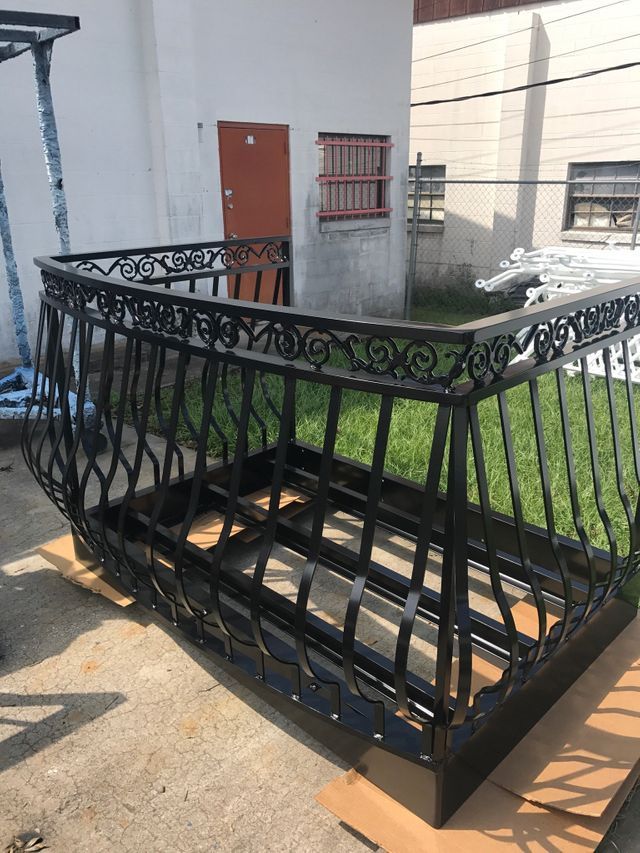 A wrought iron railing is sitting on top of a cardboard box in front of a building.