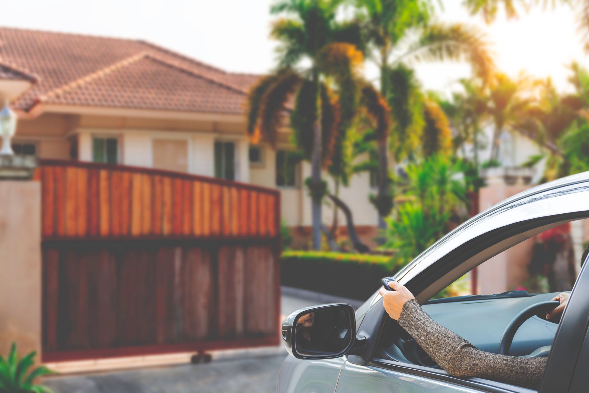 A woman is driving a car in front of a house.