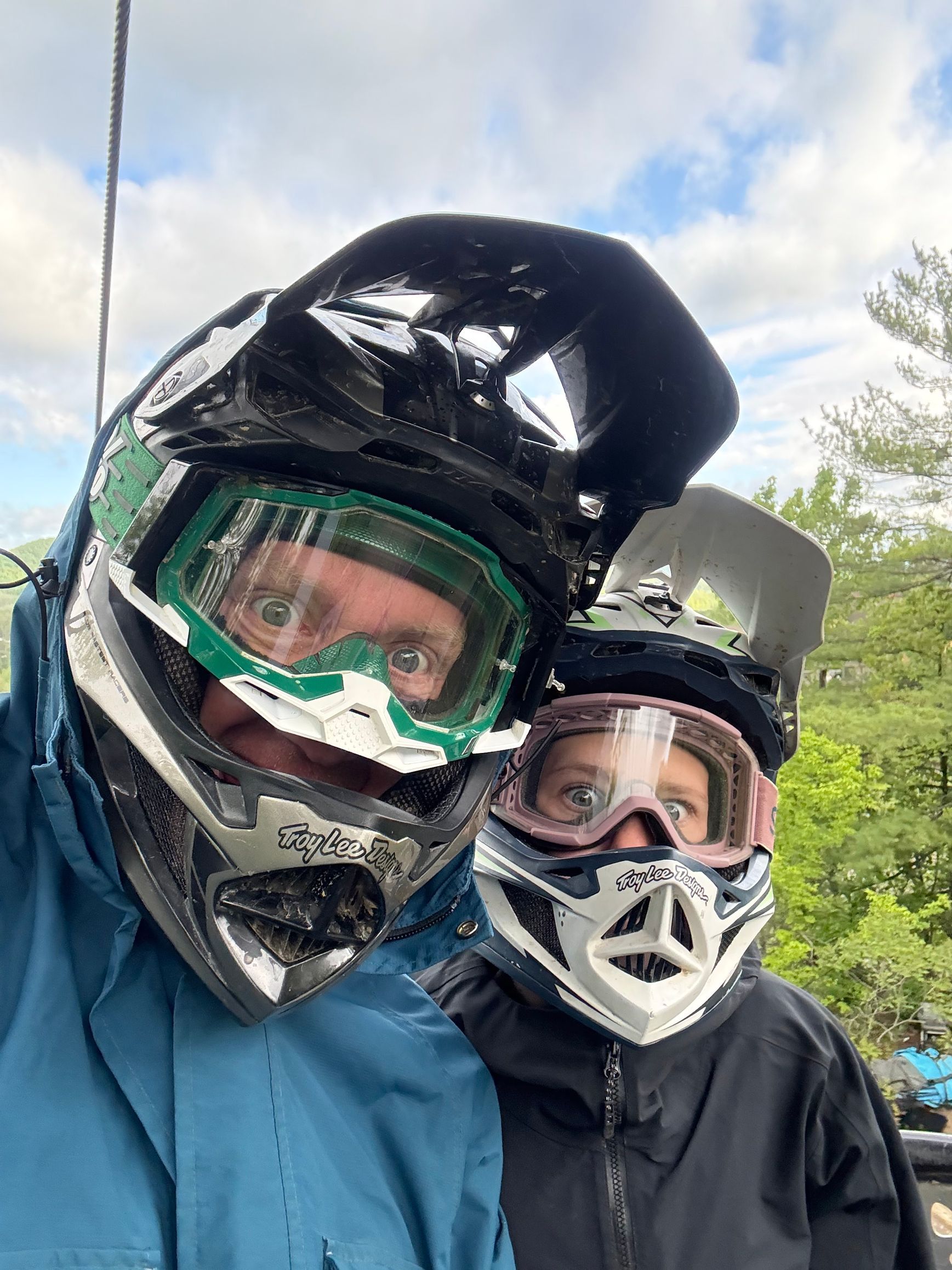 Two people in helmets and goggles, outdoors, posing for a selfie.
