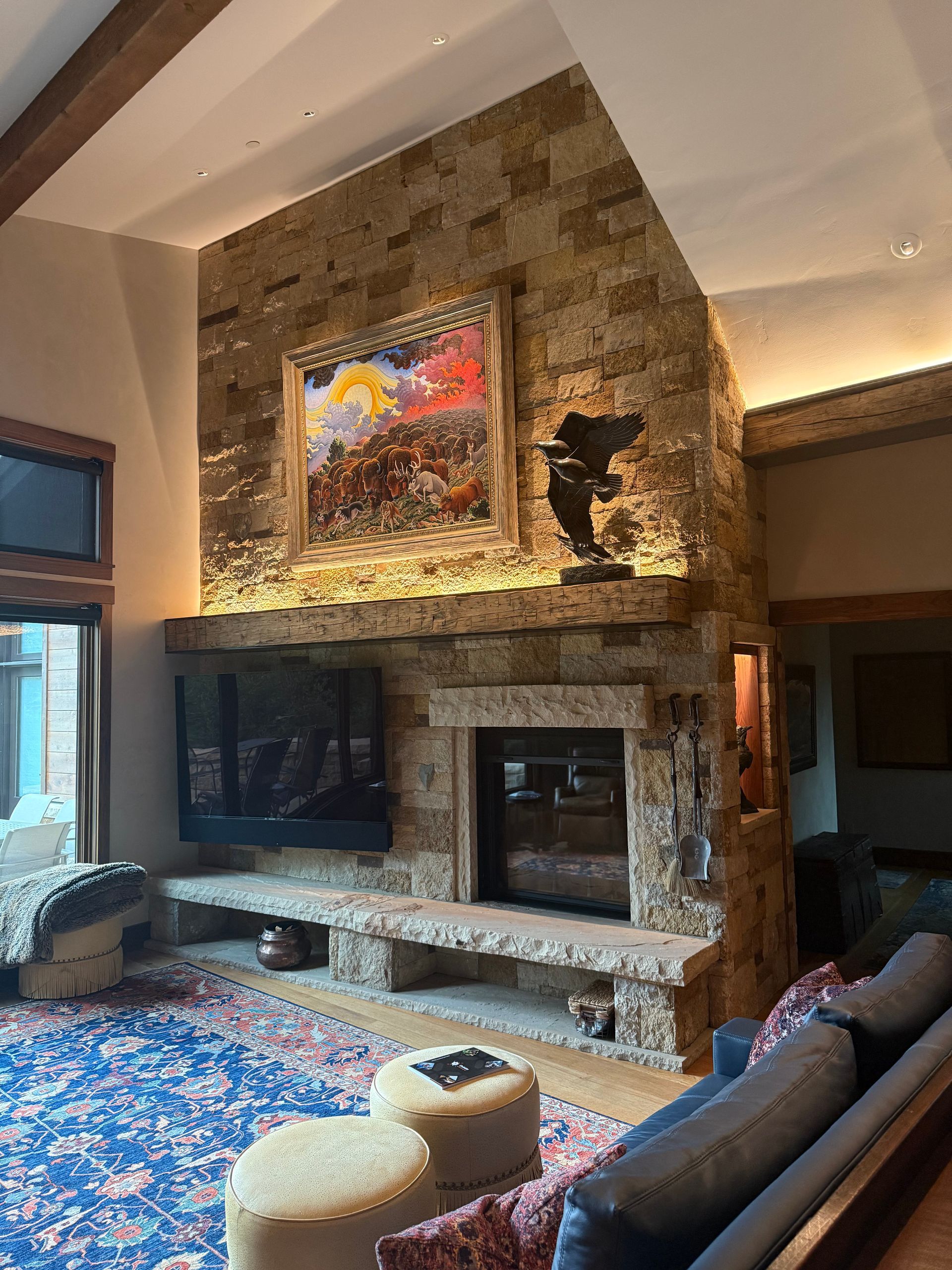 Stone fireplace with artwork, media screen, and seating in a rustic living room.