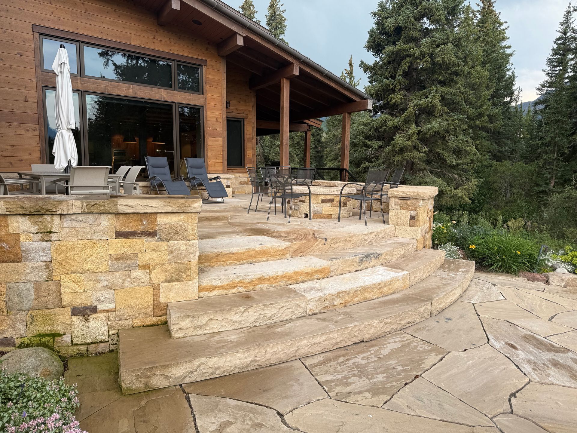 Stone steps lead up to a wooden house with an outdoor patio.