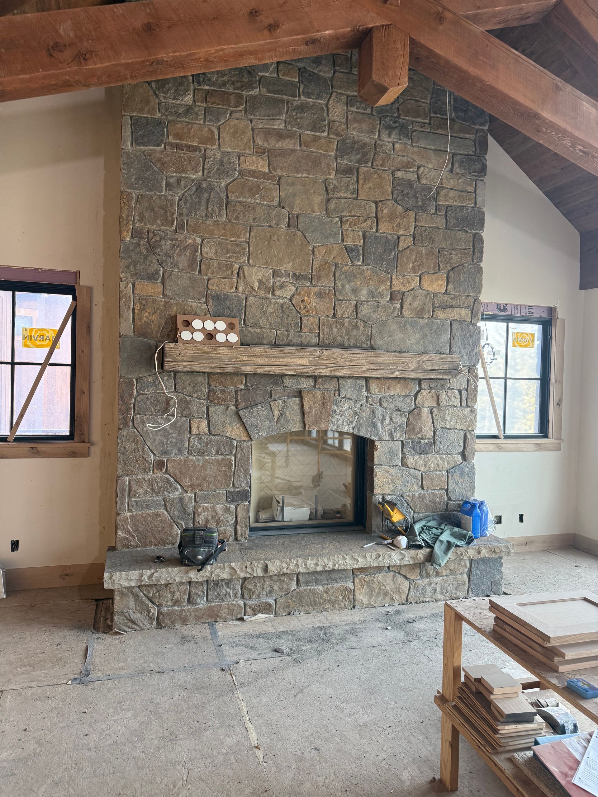 Stone fireplace with wooden mantle and exposed beam ceiling.