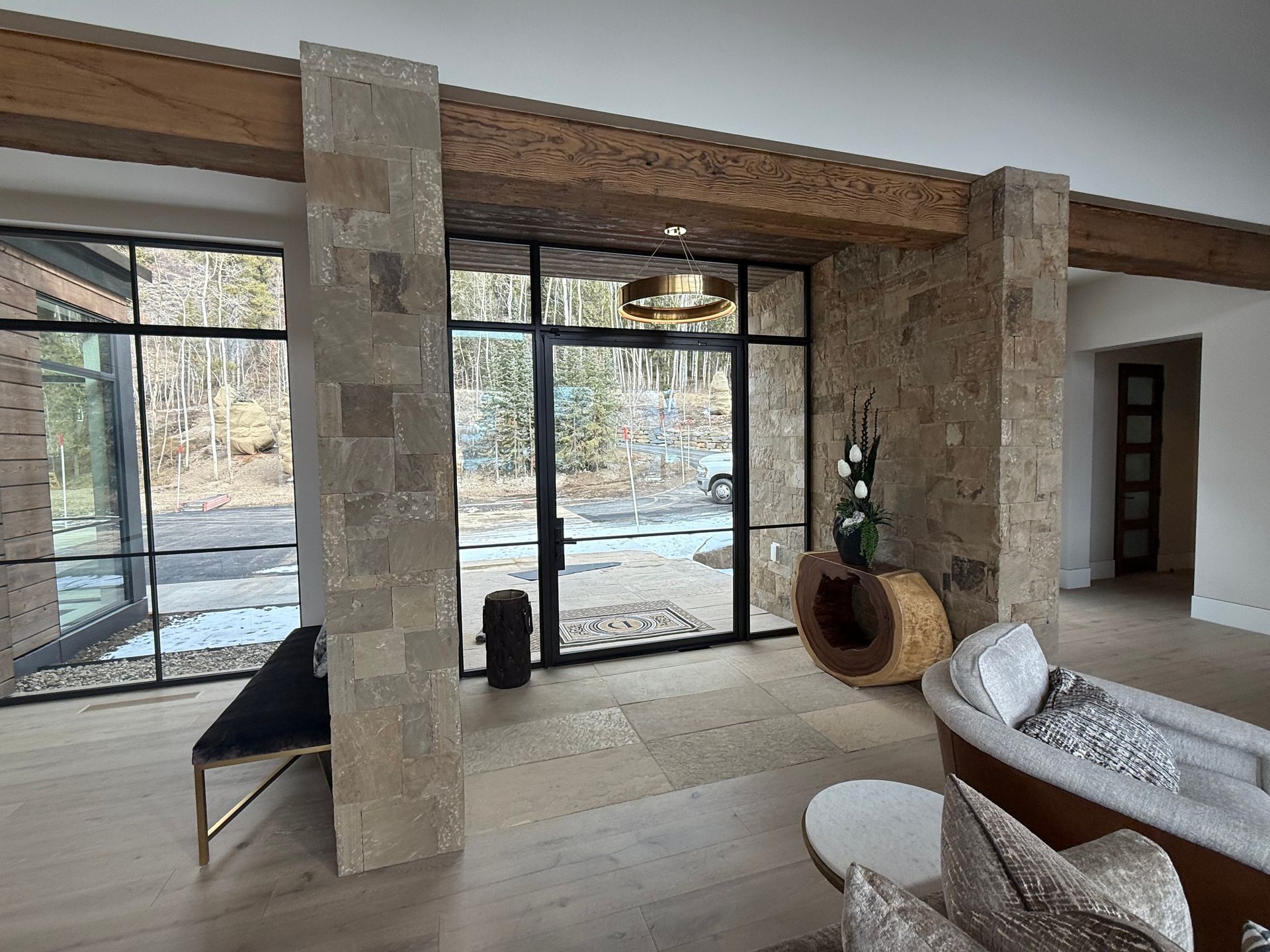 Interior with stone pillars, large windows, and modern furniture.