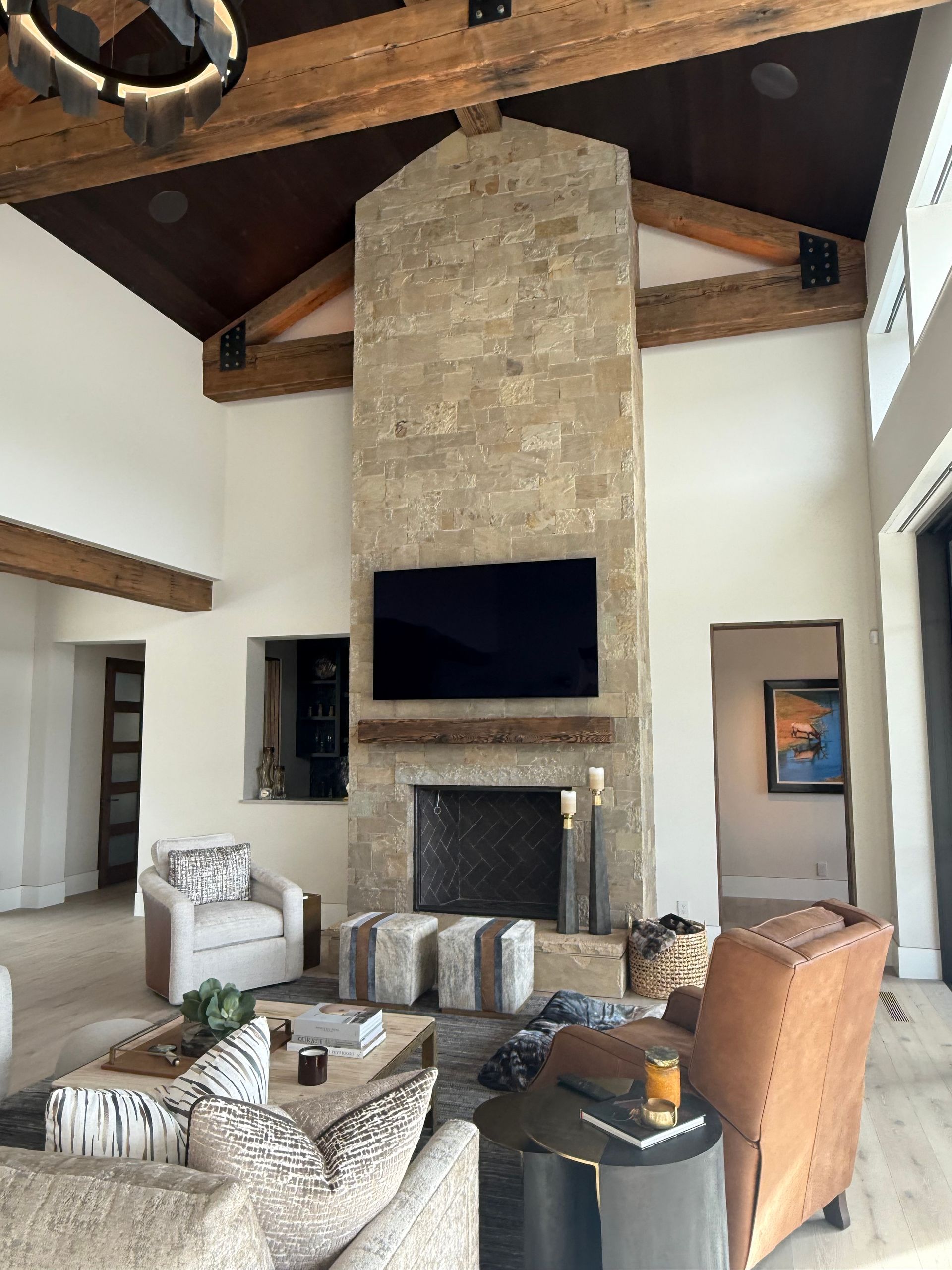 Living room with stone fireplace, TV, exposed beams, and seating.