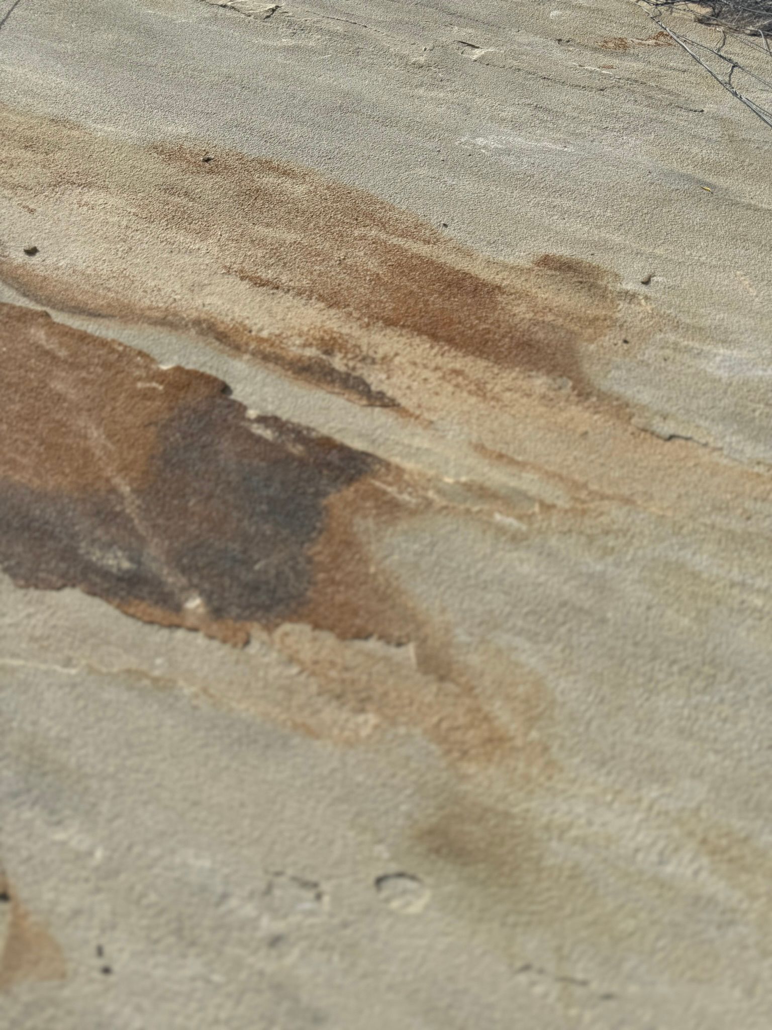 A close up of a concrete surface with a reflection of a person in it.