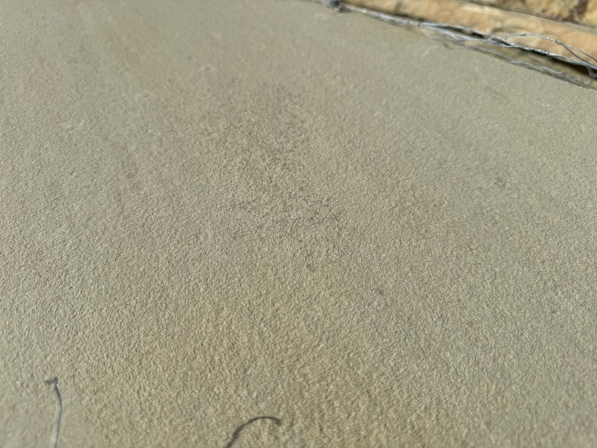A close up of a concrete surface with a brick wall in the background.