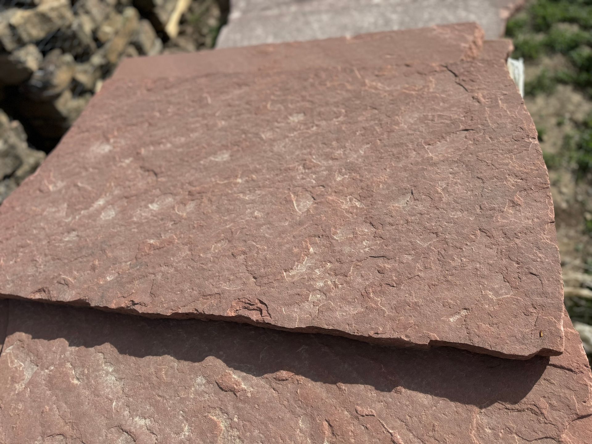 A close up of a piece of red stone sitting on top of a pile of rocks.