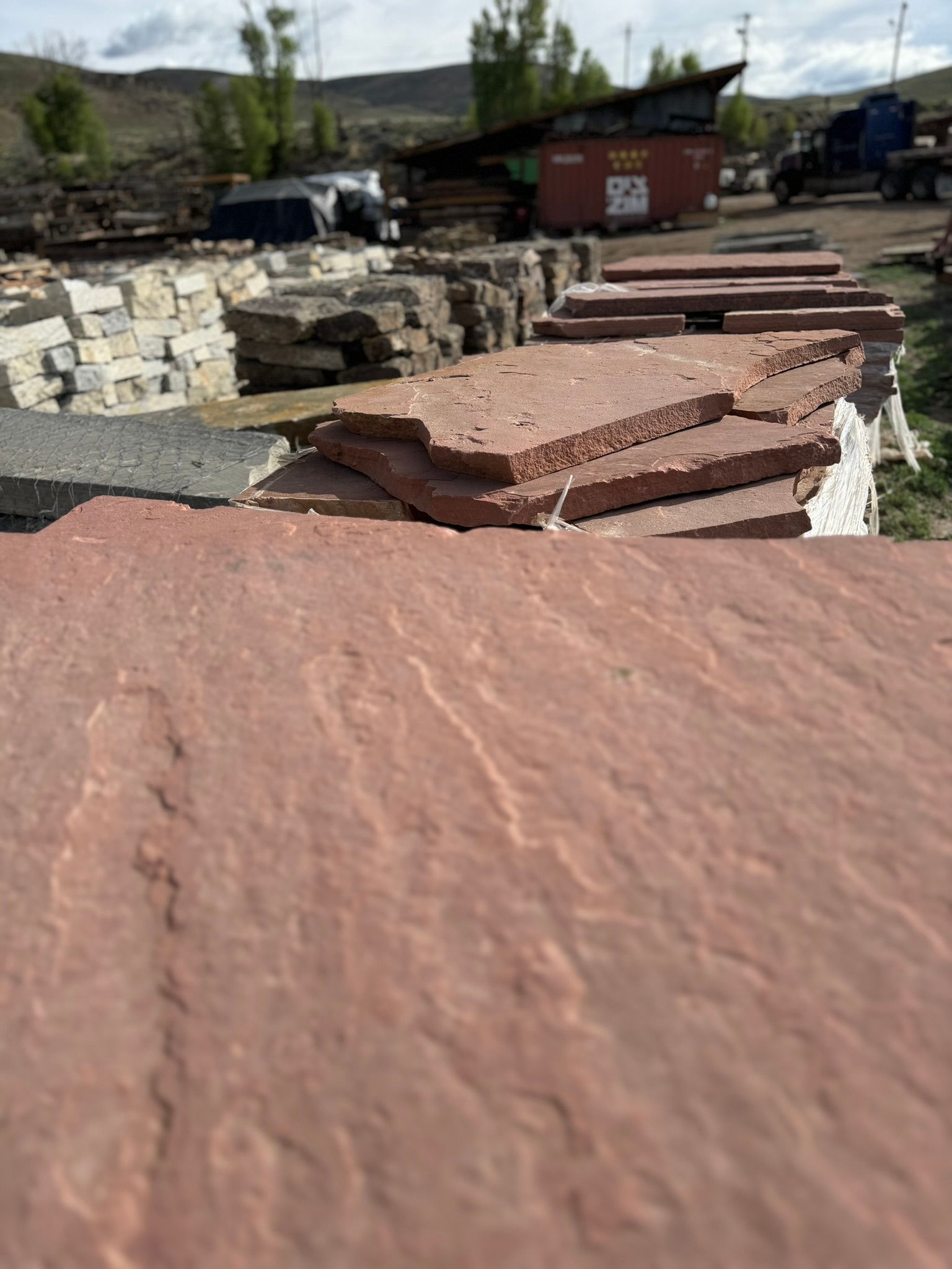 A pile of red rocks sitting on top of each other in a yard.