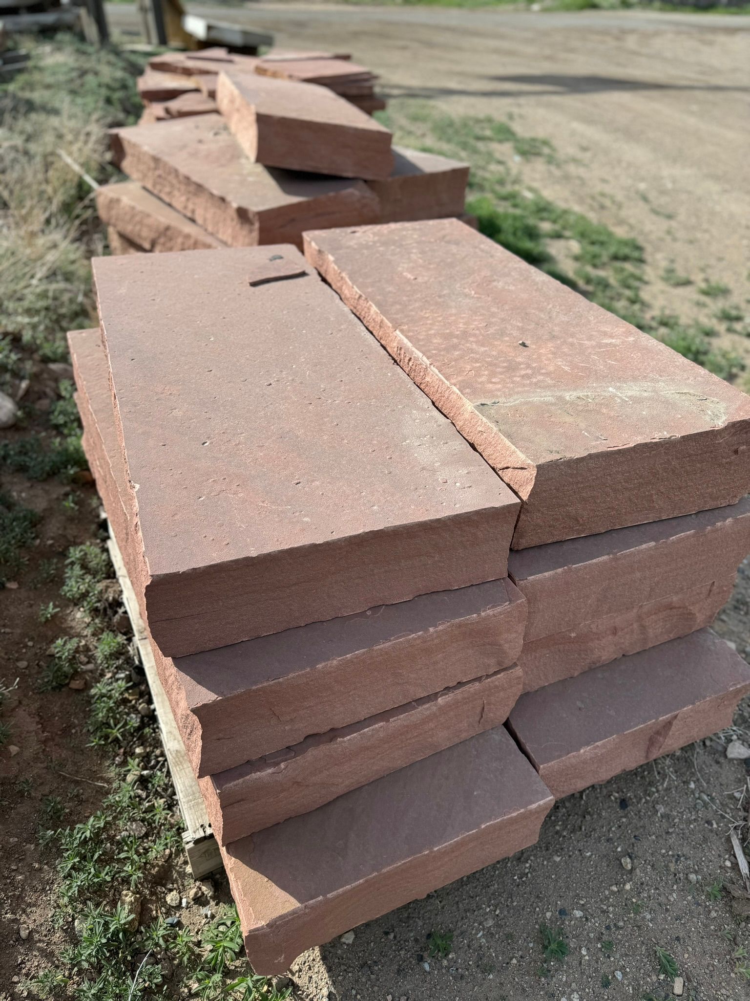 A pile of red bricks stacked on top of each other on a wooden pallet.