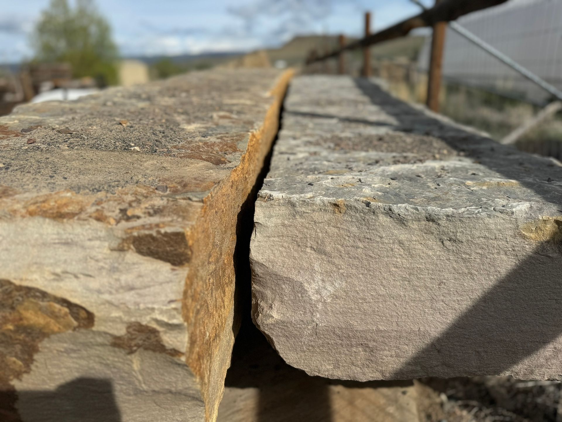 A close up of a stone wall with a fence in the background