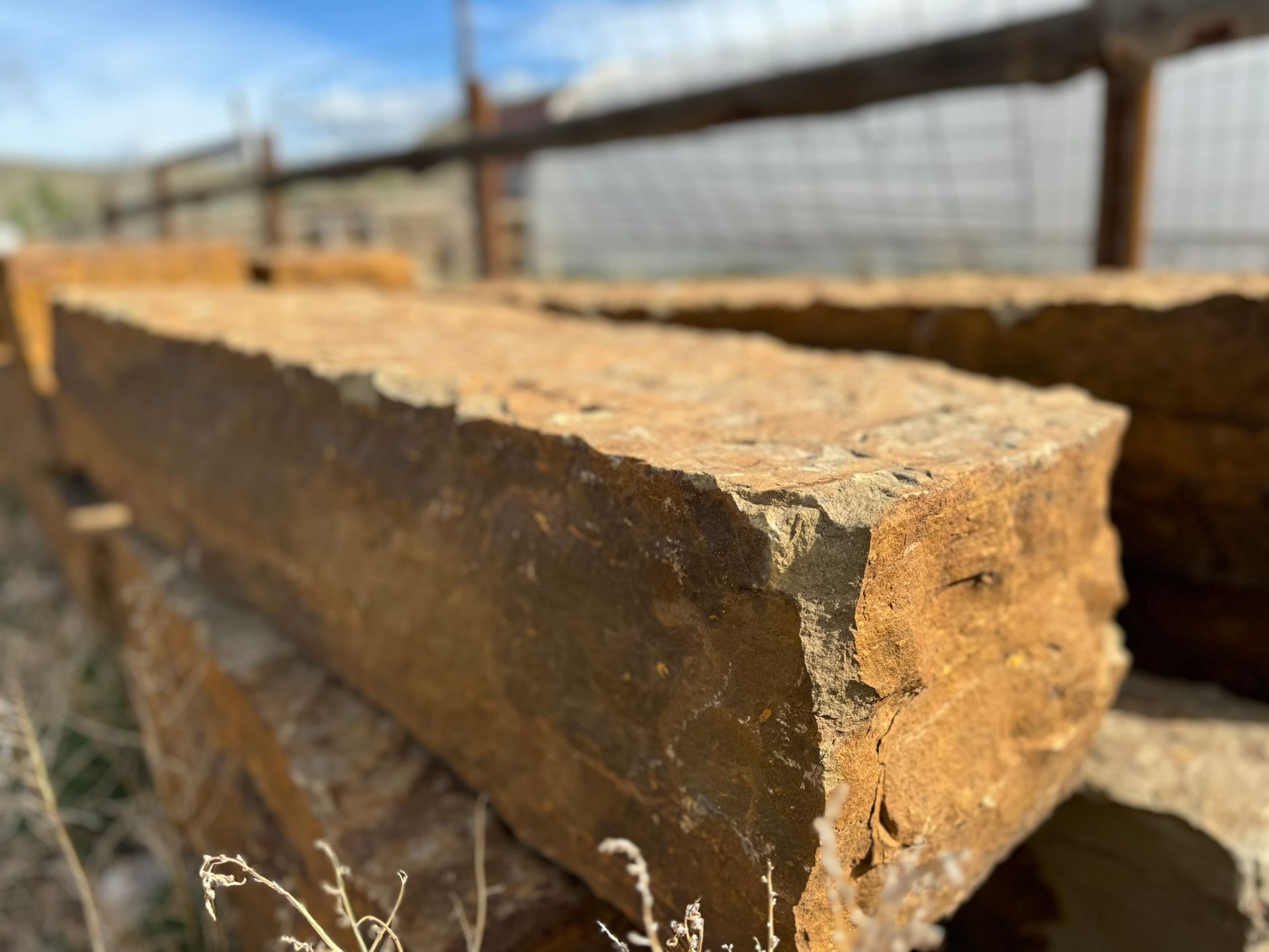 A bunch of bricks are stacked on top of each other in a field.