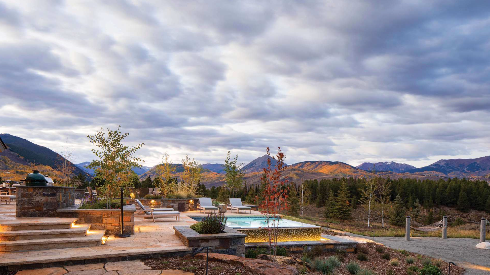 a patio with a pool and mountains in the background on a cloudy day .