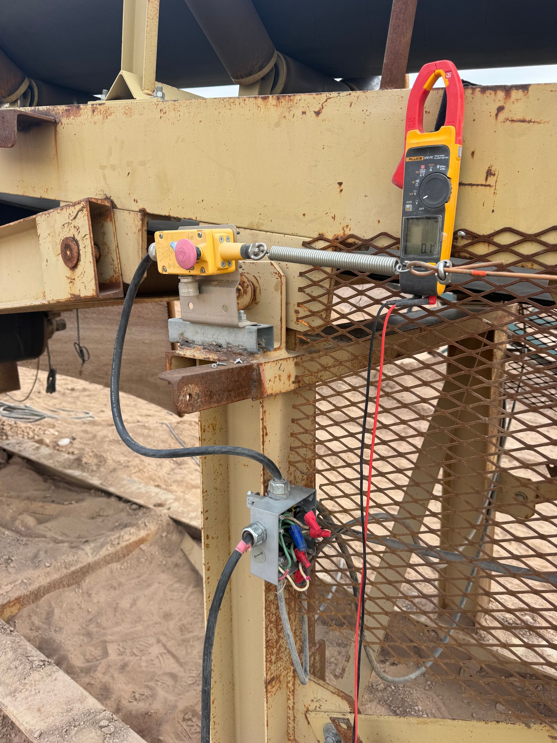 Yellow industrial equipment with electrical components and a multimeter.
