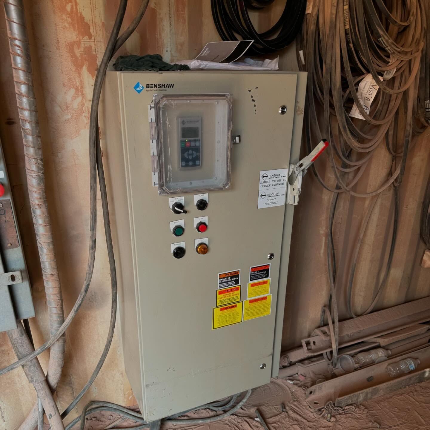 Electrical control panel with gauges, buttons, and cables in a dimly lit setting.