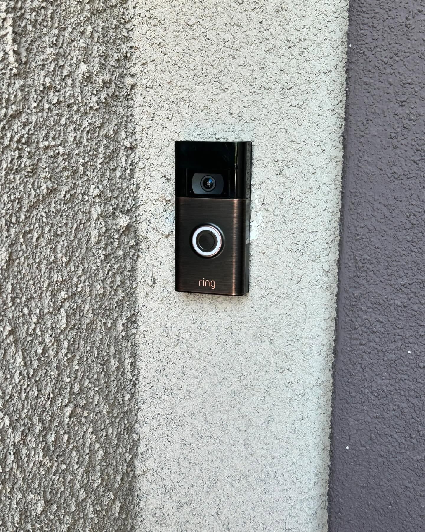 Ring video doorbell mounted on textured gray wall.