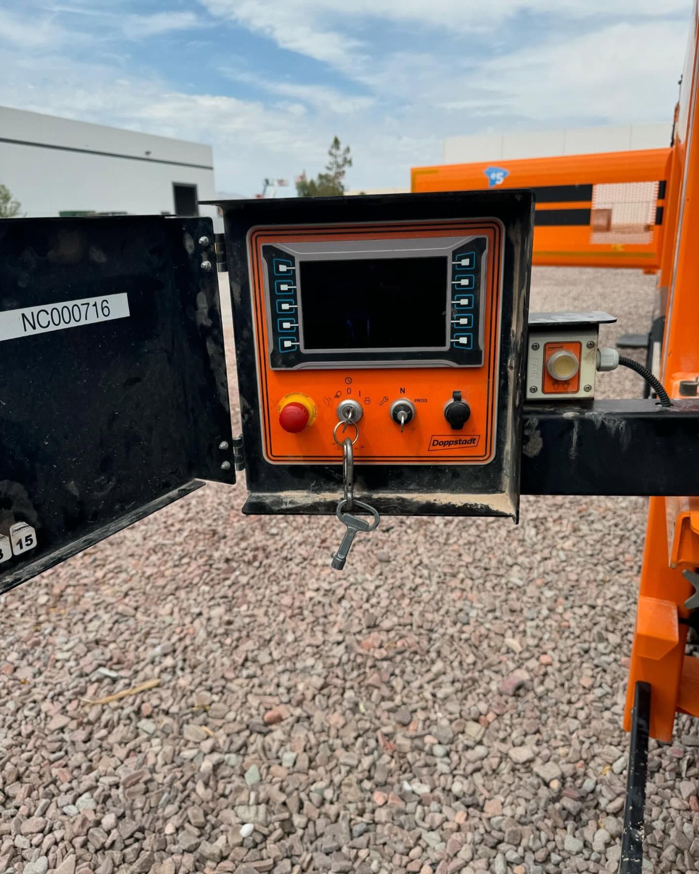 Orange control panel with screen and buttons on construction equipment, key in lock.
